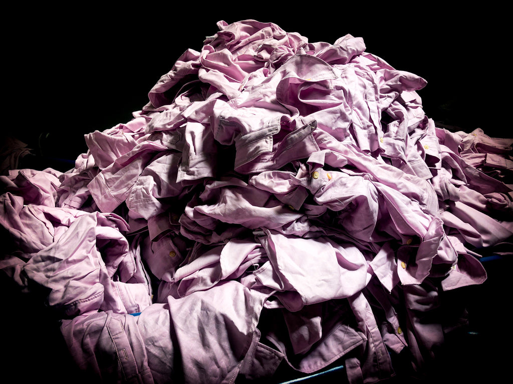 Upcycling vêtement. Tas de vieux vêtements roses empilés les uns sur les autres qui doivent être détruits. Chez Azala, nous avons fait le choix de les recycler. 