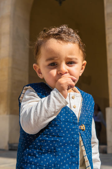 Gilet enfant Cassis-Coco Azala, sans manches, 100% recyclé et upcyclé, porté côté Cassis, taille 3 ans. Shooting extérieur, place Valois.